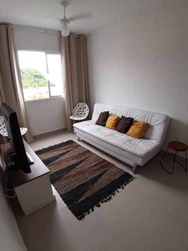 a living room with a white couch and a window at Apartamento Martinica 2 in Caraguatatuba