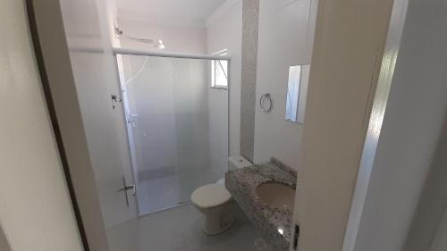 a white bathroom with a toilet and a shower at sobrado Bege - Mariscal in Bombinhas