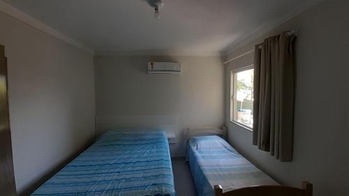 a small bedroom with two beds and a window at sobrado Bege - Mariscal in Bombinhas