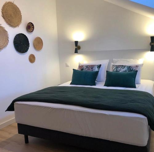 um quarto com uma cama grande e almofadas verdes em Gîte de la moinette em Azé
