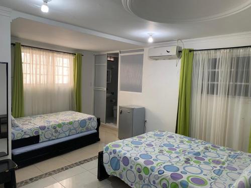 a bedroom with two beds and green curtains at Posada Cocos Place in San Andrés