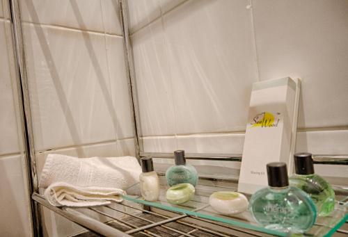 a shelf with glass bottles and a box on it at Holcombe House Guest House in Llandudno
