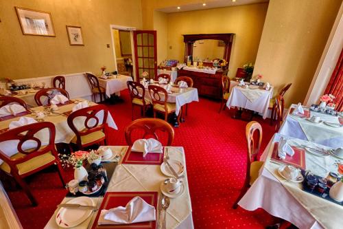 a dining room with tables with white tablecloths at Holcombe House Guest House in Llandudno
