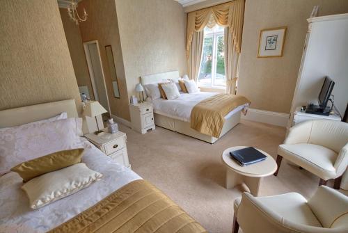a hotel room with two beds and a chair at Holcombe House Guest House in Llandudno