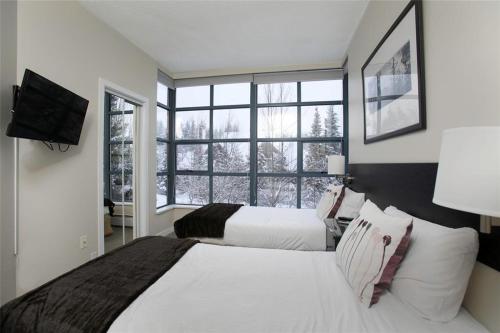 a bedroom with two beds and a large window at Alpenglow Lodge by Bill in Whistler