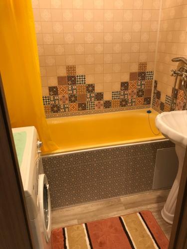 a bathroom with a yellow tub and a sink at Квартира Комсомольская, 70 in Bratsk