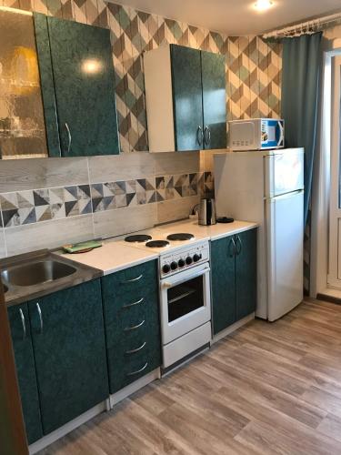 a kitchen with green cabinets and a white stove and refrigerator at Квартира Комсомольская, 70 in Bratsk
