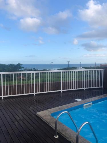a deck with a swimming pool and a fence at Condomínio residencial mar azul in Imbituba