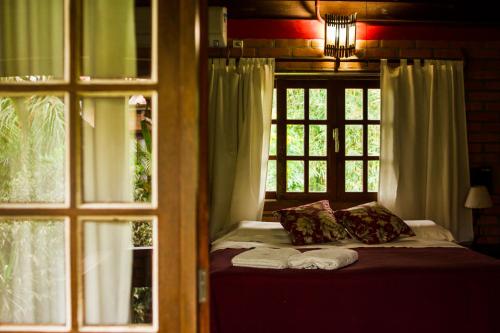 a bedroom with a bed and a window with towels on it at Pousada Além do Jardim in Praia do Rosa