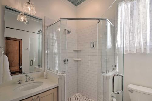 a white bathroom with a shower and a sink at Bright Galveston Cottage Close to Beach and Strand in Galveston