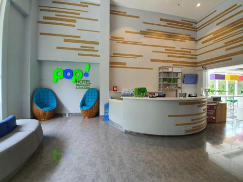 a lobby with a reception desk and blue chairs at POP! Hotel Diponegoro in Surabaya