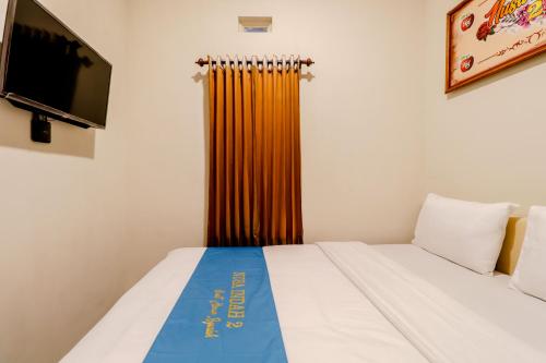 a small room with a bed and a tv at Guesthouse Nusa Indah Syariah 2 in Batu