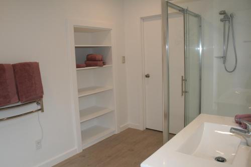 uma casa de banho branca com um chuveiro e um lavatório. em Bridgehaven Guesthouse em Okoroire