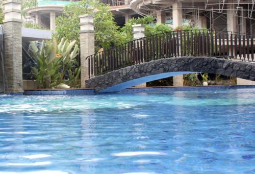 a bridge over a swimming pool with blue water at Apartemen Grand sungkono Lagoon Venetian. in Surabaya