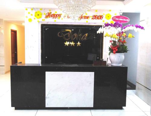 a black and white reception desk in a room with flowers at Doha 2 Hotel Saigon Airport in Ho Chi Minh City