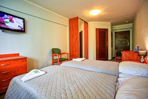 a hotel room with two beds and a flat screen tv at Hotel Karolinka in Karpacz