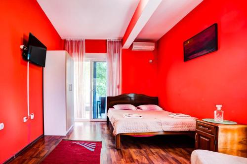 a bedroom with red walls and a bed with pink pillows at Villla Elkom, App 10 in Ulcinj