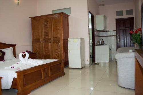 a bedroom with a bed with a dresser and a refrigerator at Hoa Phat Hotel & Apartment in Ho Chi Minh City