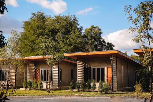 a house with a brick facade and trees at BaanKampu Resort in Pak Chong