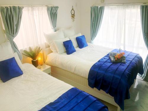two beds in a bedroom with blue and white at 海の見える高台にあるテラス付きハウス!! 家族旅行に最適!! in Okinawa City