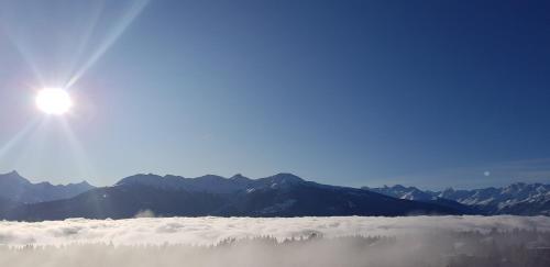 a view of the sun above the clouds with mountains at Hôtel Splendide in Crans-Montana