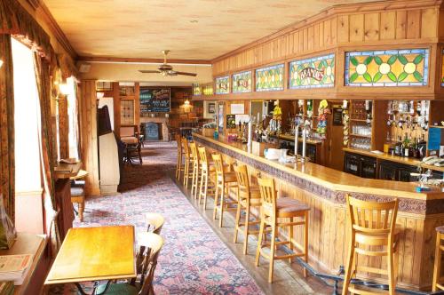 a bar in a restaurant with wooden walls and chairs at Radstock Hotel near Bath in Radstock