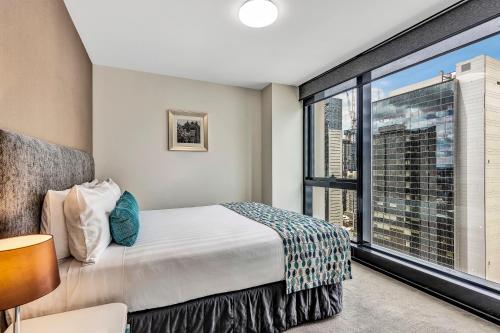 - une chambre avec un lit et une grande fenêtre dans l'établissement Pegasus Apart-Hotel, à Melbourne