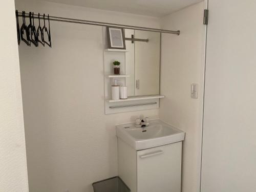ein weißes Badezimmer mit einem Waschbecken und einem Spiegel in der Unterkunft CASA KUNISAKU in Machida