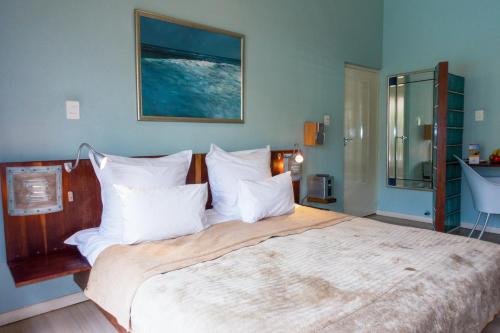 1 dormitorio con 1 cama grande con almohadas blancas en Rosedene Lodge - 24h solar with pool and garden, en Ciudad del Cabo