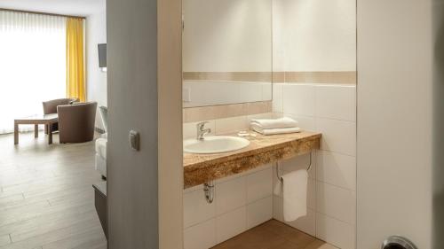 een badkamer met een wastafel en een spiegel bij Hotel Göller in Hirschaid