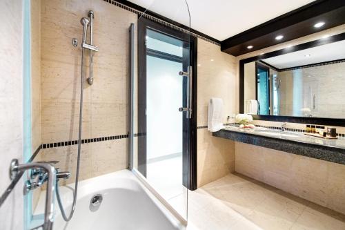 een badkamer met een bad en een glazen douche bij Mitsis Faliraki in Faliraki