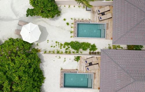 an overhead view of a beach with an umbrella and chairs at Brennia Kottefaru Maldives in Raa Atoll