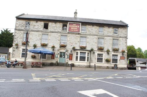 a large stone building with a blue umbrella in front of it at Radstock Hotel near Bath in Radstock