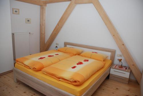 a bed with yellow sheets and red flowers on it at Appartment Gsolerhof in Castelrotto