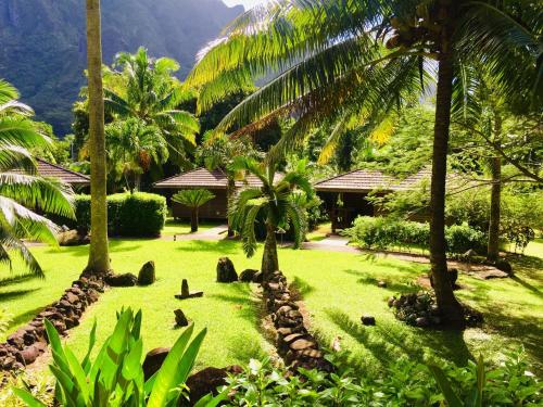 a garden with palm trees and a resort at Eco Lodge Village Temanoha in Paopao