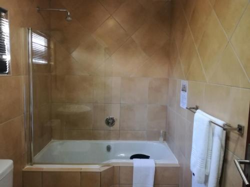 a bathroom with a bath tub and a shower at Belmont Guesthouse in Bloemfontein