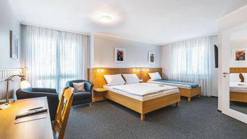 a hotel room with a bed and a chair at Dorint Parkhotel Siegen in Siegen