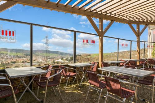 a patio with tables and chairs and a view of the city at The Originals City, Hôtel L'Acropole, Saint-Etienne Sud in La Ricamarie