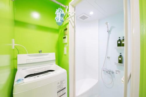 a green bathroom with a washer and a shower at bmj Hyakunincho in Tokyo