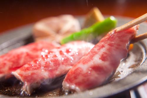 three pieces of meat on a plate with chop sticks at Yufuin Santoukan in Yufuin