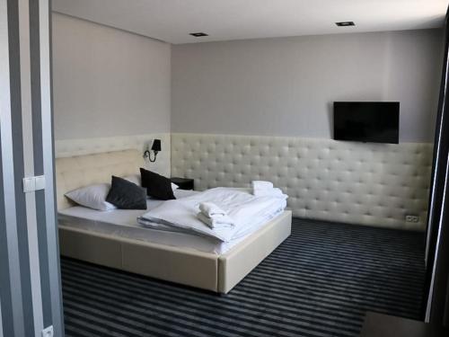 sypialnia z łóżkiem z białą pościelą i telewizorem w obiekcie Biały Dwór w mieście Rychwał