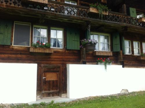 a wooden house with windows and flowers on it at Ferienwohnung im Grünen in Grindelwald