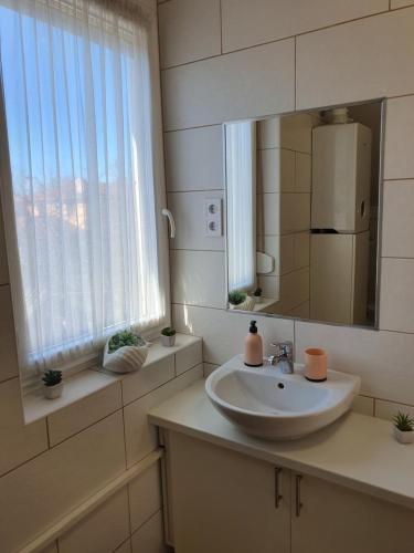 a bathroom with a sink and a mirror and a window at Bella Apartman in Szeged