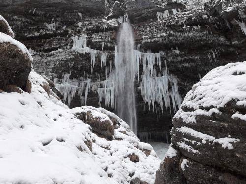 a waterfall is covered in snow and ice at Apartma Pika in Mojstrana