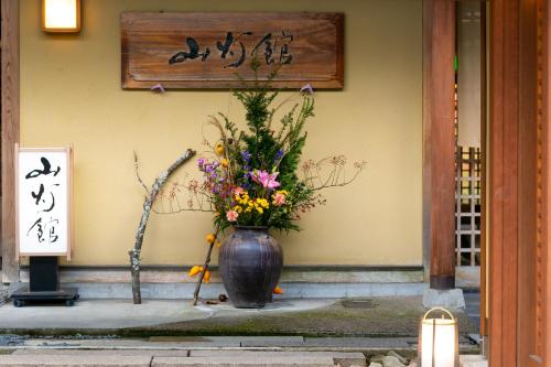 a vase filled with flowers sitting in front of a building at Yufuin Santoukan in Yufuin