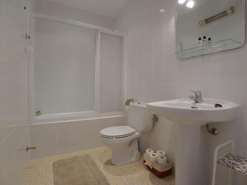 a white bathroom with a toilet and a sink at Torrox Beach Club in Torrox Costa