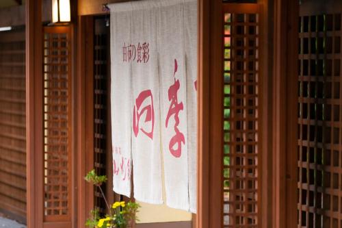 a window with a white towel with writing on it at Yufuin Santoukan in Yufuin