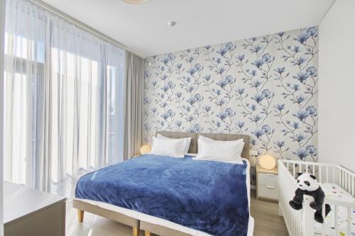 a bedroom with a crib and blue and white wallpaper at Asian Magnolia Boutique Apartments in Druskininkai