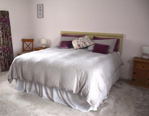 um quarto com uma grande cama branca com almofadas roxas em Tuck Mill Cottage em Castlewellan