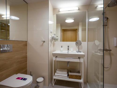 ein Bad mit einem Waschbecken, einer Dusche und einem WC in der Unterkunft VacationClub – Seaside Apartament 348 in Kołobrzeg